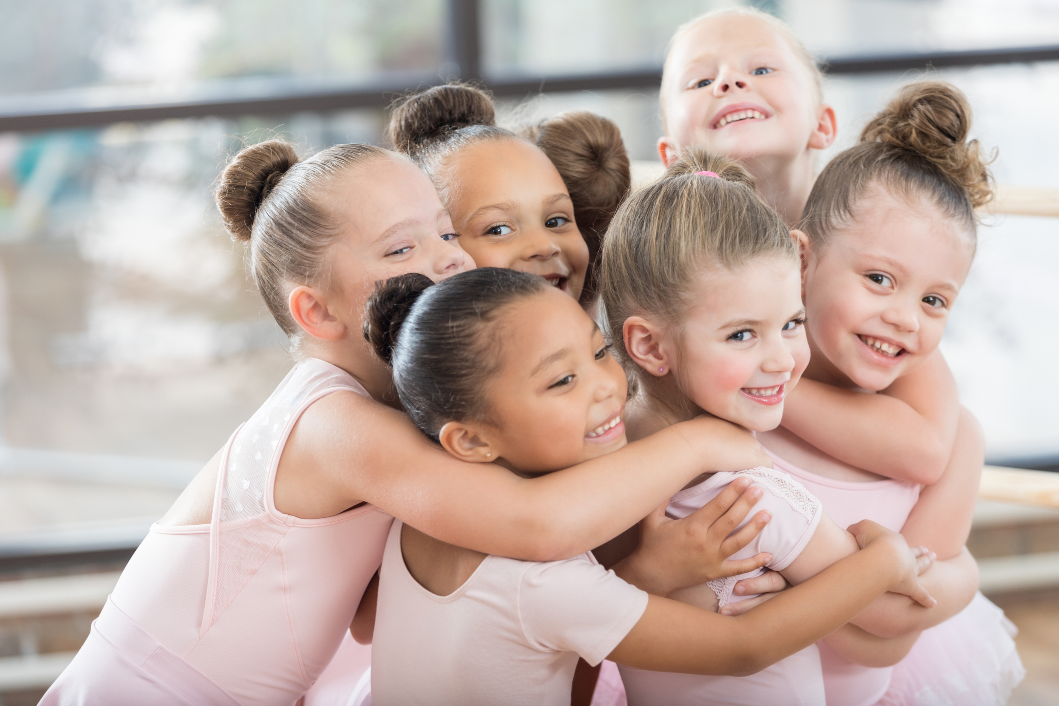Young ballerinas form a smiling group hug